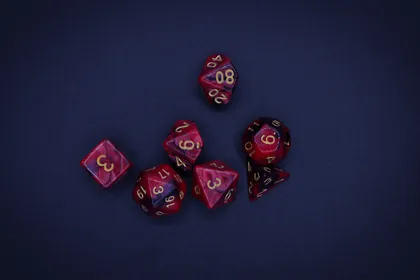 A seven-dice polyhedral set in swirled red and purple, laid out on dark blue felt