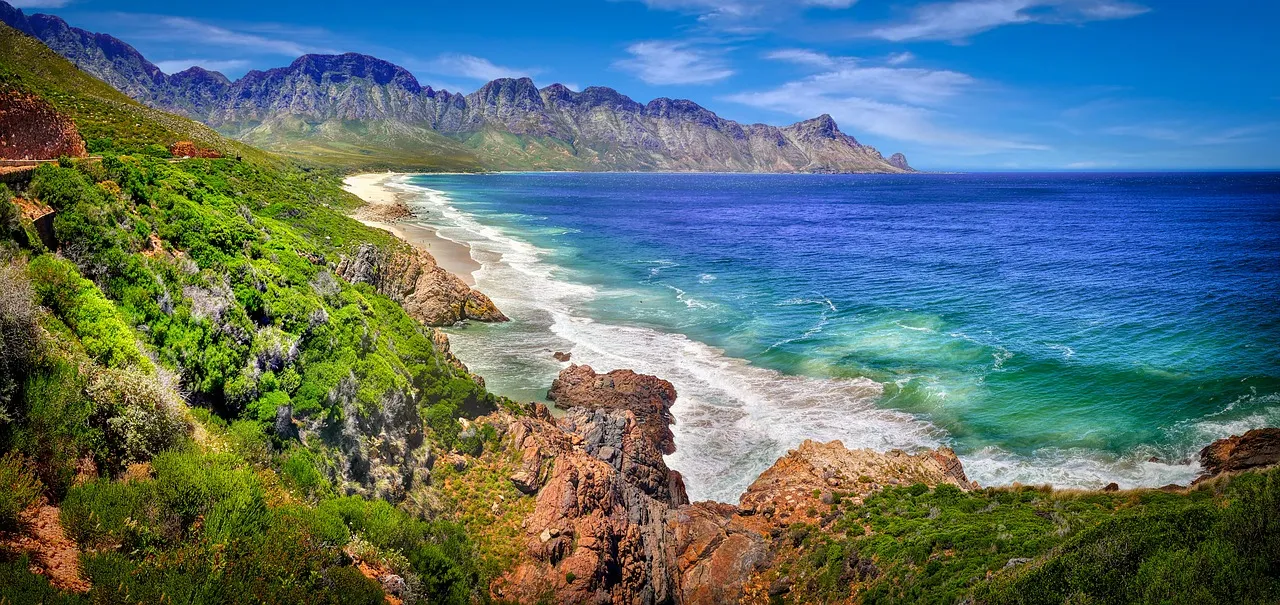 Green mountains dropping straight into a turquoise sea along a rocky coast